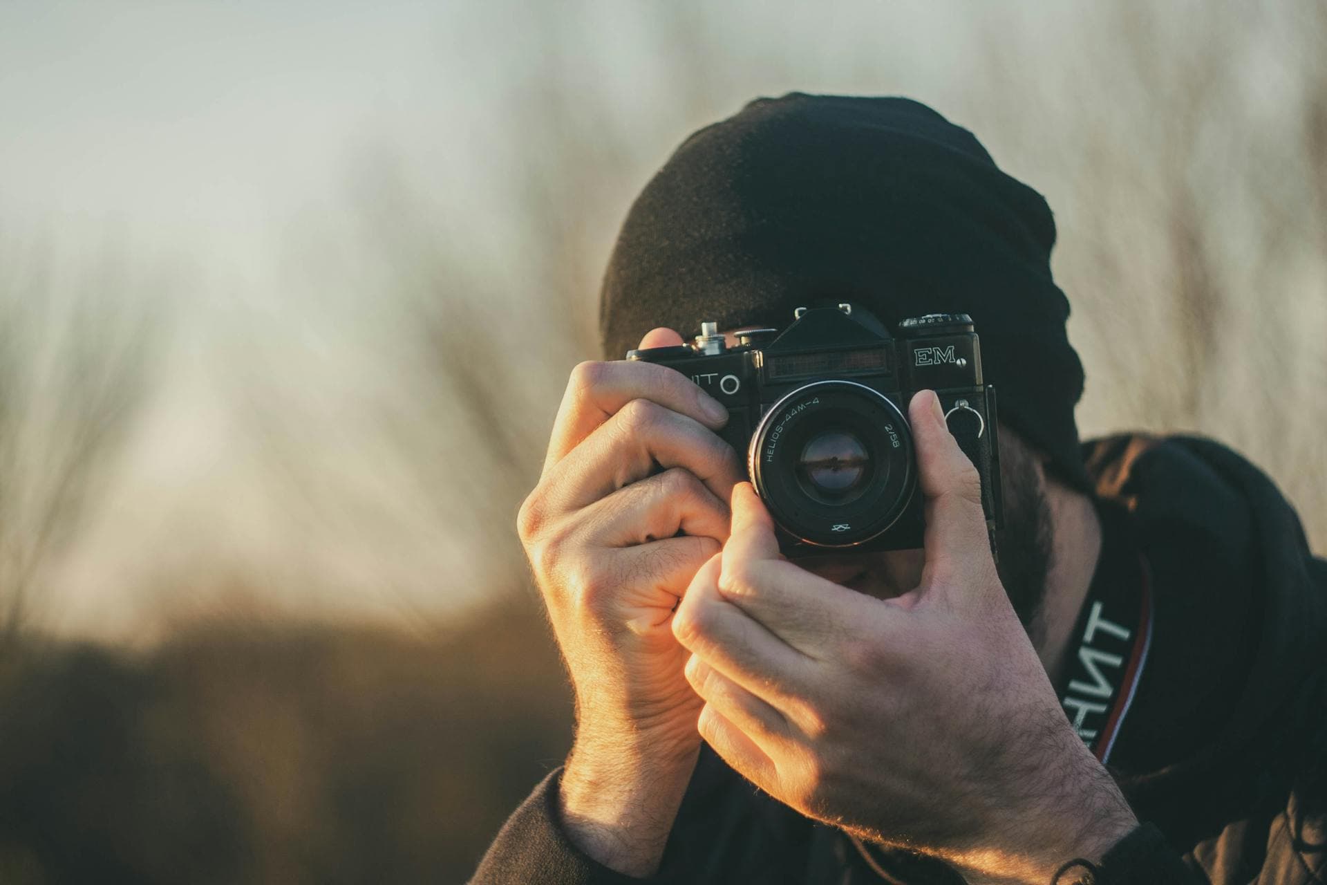 Person photographing a city street with a film camera