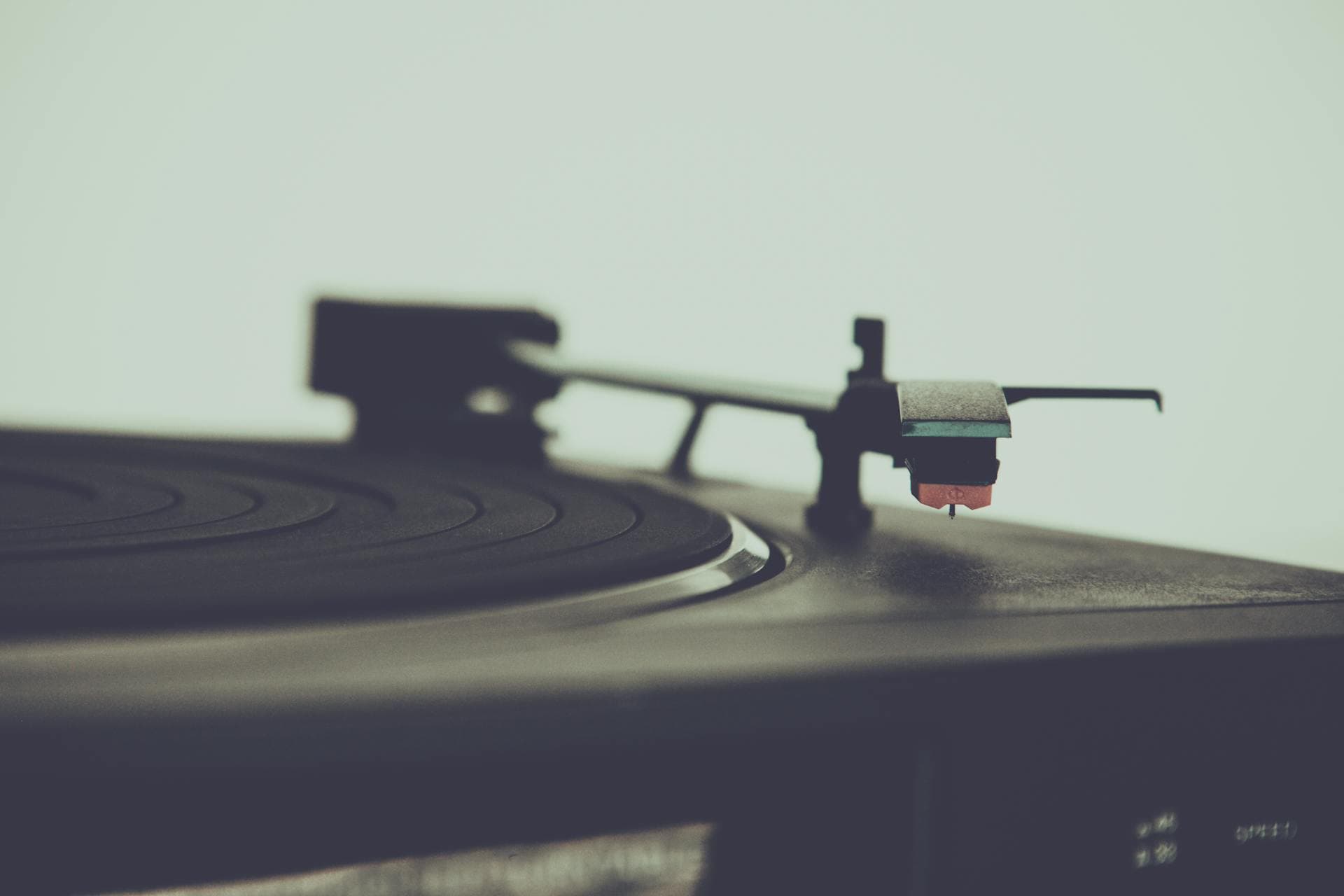 An overhead view of a turntable shows the platter, tonearm, and stylus assembly