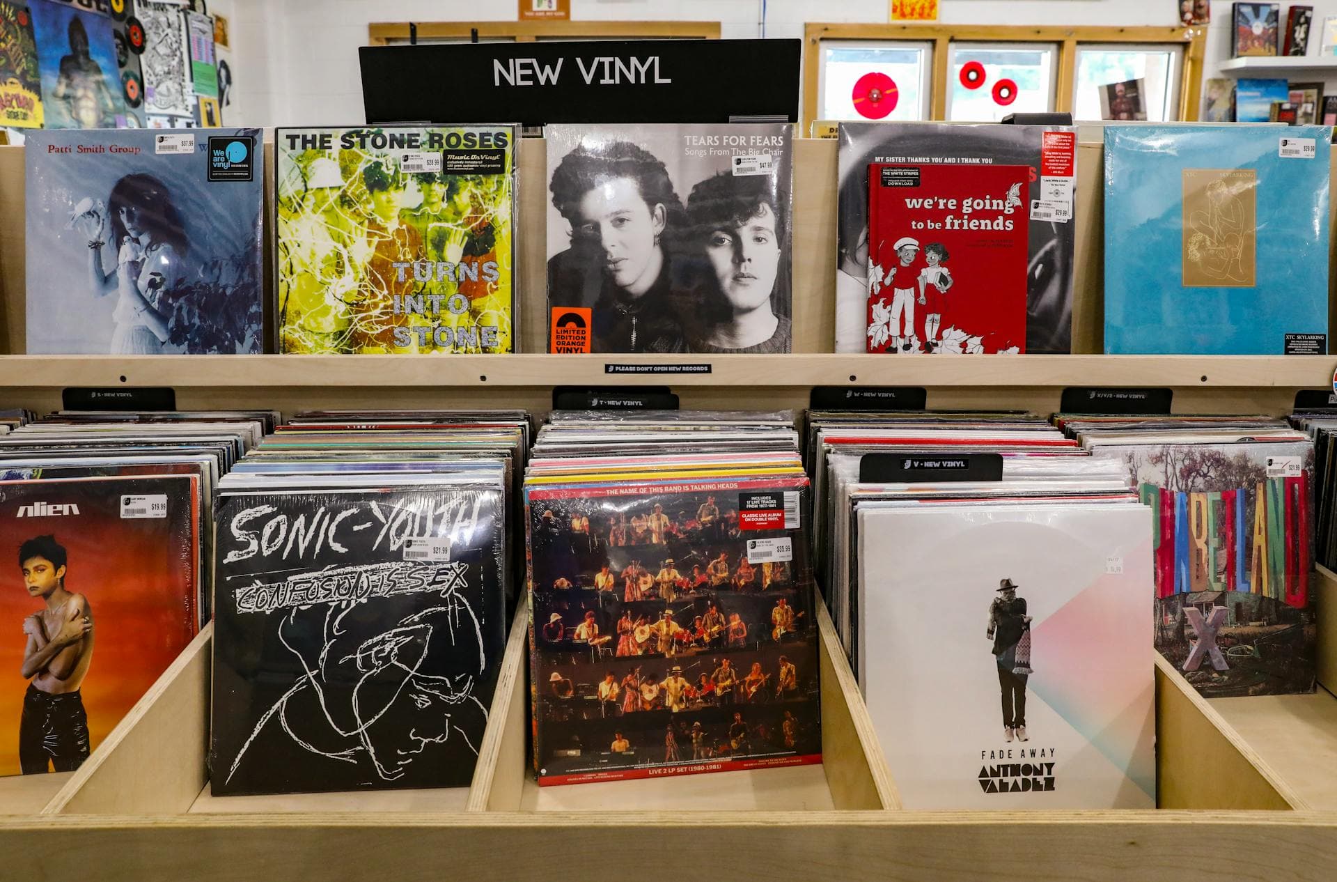 Wooden bins packed with vinyl records line the wall of a record shop